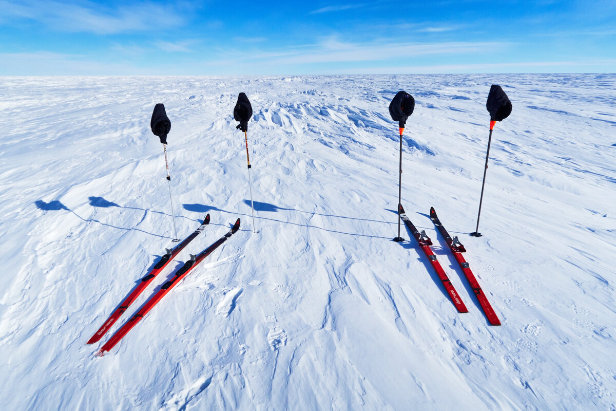 Two sets of skis, poles, and pogies await their skiers