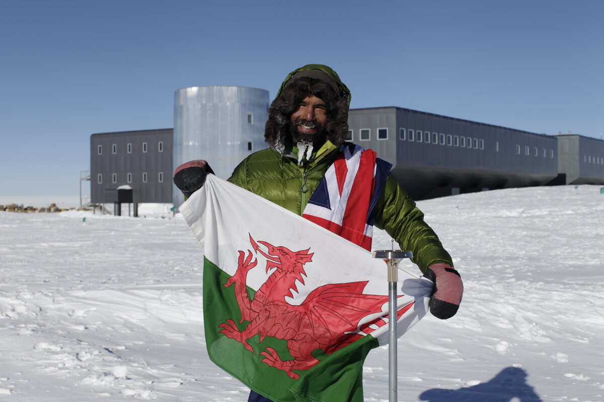 Skier holds a Welsh flag at the Geographic South Pole