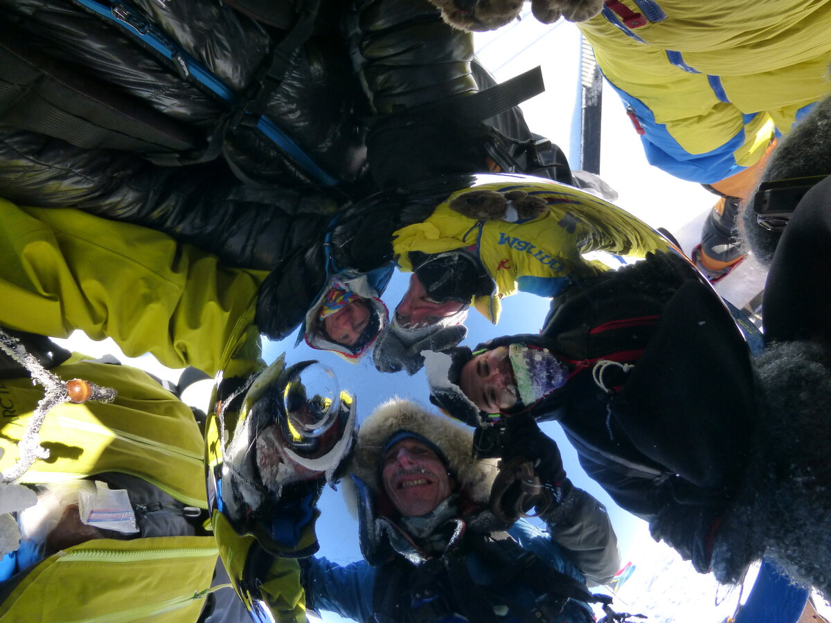 Ski team faces reflected in the Ceremonial South Pole